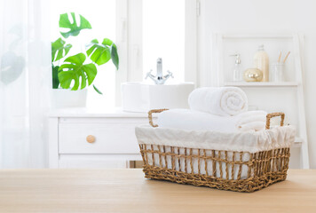 Towels in wicker basket on table with bathroom windowsill background