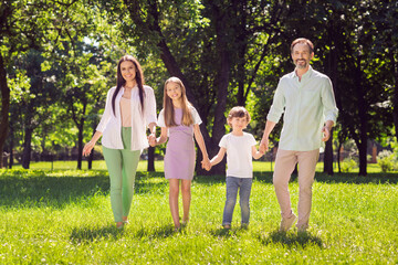 Portrait of attractive adopted foster cheerful family dad mom spending time on green grass walking fresh air outdoors