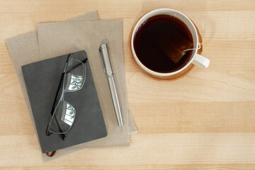 Notebook, recycled paper, pen and tea cup on business desktop.