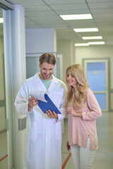 Fototapeta premium Smiling physician and a joyful woman scrutinizing a document