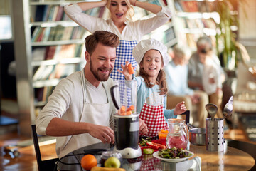 A little daughter helping her father while preparing a meal at home together. Family, together, home