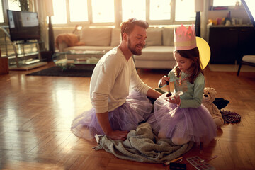 A little daughter and her father putting up makeup while preparing for a ballet practice at home. Family, together, home