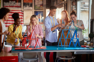 two group of employees making paper towers, separated in different competitive teams.