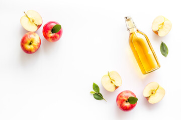 Apple cider vinegar in glass bottle with fresh red apples