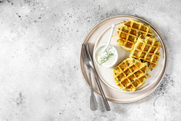 Homemade zucchini waffles in a white plate on a light gray culinary background top view from a copyspace	