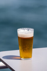 Glass of draught beer served outdoor on terrace with sea view