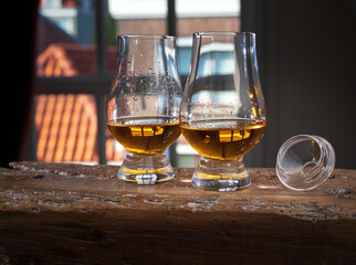 Dram of single malt scotch whisky served in tasting glass with view on old window and houses