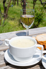 Lunch with homemade white asparagus soup and Dutch white wine served outdoor on green meadow with vineyard, asparagus and wine production farm in Netherlands