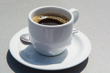 White cup of black coffie on gray background