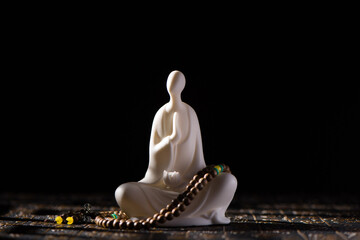 A small white Buddha figure sits on black background