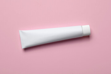 Blank tube of toothpaste on pink background, top view