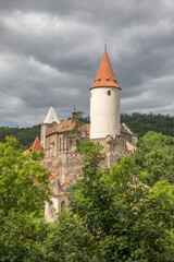 Fototapeta premium sunlit medieval castle with a round tower on a background of steel-gray clouds