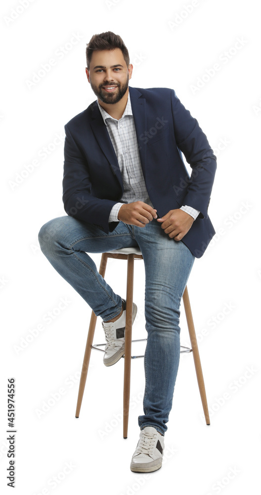 Poster Handsome young man sitting on stool against white background