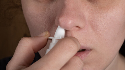 remedy for the common cold, the girl puffs a nasal spray in the nose.