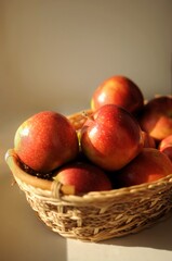 Straw basket with rea ripe apples on light background. Home harvest cope space