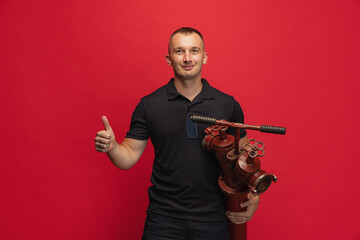 Portrait of young smiling man with fire hydrant posing over red background.