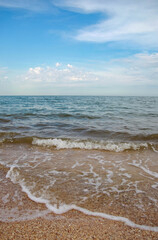 Lace waves on the sand, blue sea and beautiful blue sky with white clouds, quiet beach without people