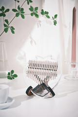 Kalimba or mbira is an African musical instrument. Glass Kalimba 17 keys on stand and on decoration white table with green leaves. Concept style. Music concept