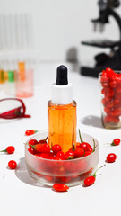 Goji berry seed oil in glass dropper bottle and fresh goji berries on table.