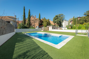 Fototapeta na wymiar Summer pool surrounded by green grass with white marble go on a sunny day