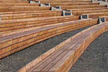 Empty contemporary wooden benches in open air outdoor city public event space.Modern urban public vandal proof resting furniture.Public seats,rhythms and perspective