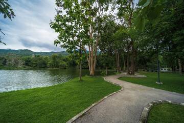 Road pathway in the park for relaxing walking jogging landscape lake views at Ang Kaew Chiang Mai University in nature forest Mountain views spring blue sky background with white cloud.