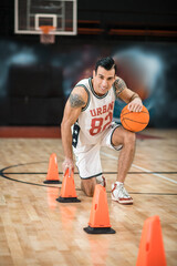 Naklejka premium Tattoed man in white shportswear playing basket-ball