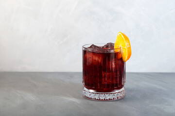 Glass of Boulevardier cocktail with big ice cubes and orange slice. Classic alcoholic drink...