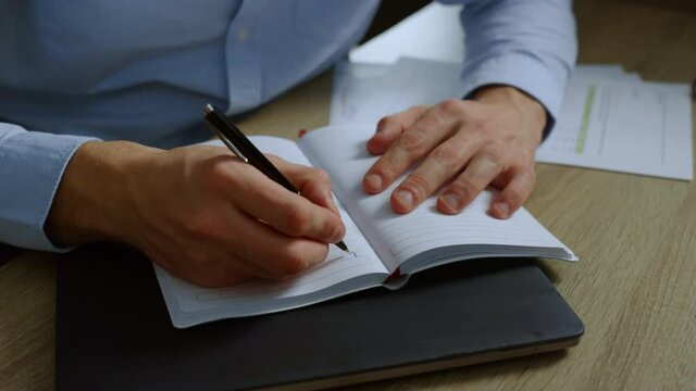Businessman hands making notes in notebook. Executive writing schedule in diary