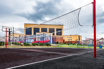 Volleyball court with net near school building.