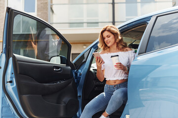 Young woman in casual clothes with her electromobile outdoors at daytime