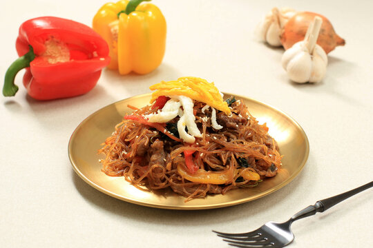 Close Up Korean Authentic Cuisine, Japchae or Glass Noodles Stir Fried with Vegetables in Gold Plate. Eat Daily or at Chuseok Day