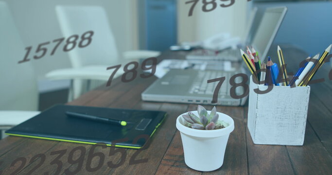 Image of numbers changing over desk with tablet and laptop