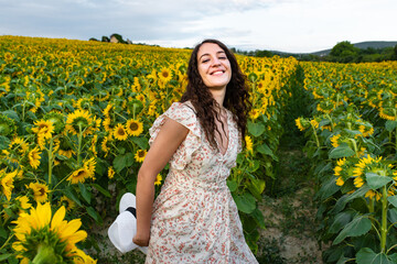 Smiling young woman walking in the middle of a field of sunflowers