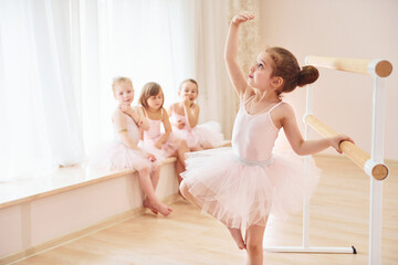 Little ballerinas in pink uniforms preparing for performance
