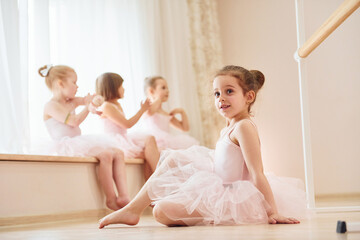 Girl sits on the floor. Little ballerinas preparing for performance by practicing dance moves