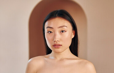 Naklejka premium Young serious asian woman standing indoors