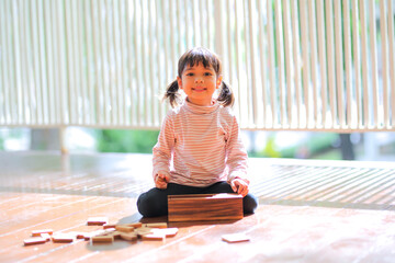 little girl two asian girls playing wooden stacks at  home  which increases the development and enhances outside the classroom learning skills concept.