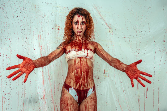 Bloody woman in a room with blood-filled plastics with open arms