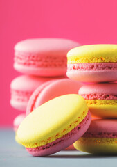 Pink yellow macaroons cakes on gray blue table background, place for text, trendy minimalism style, selective focus