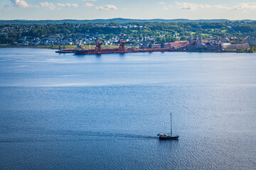 Sailboat and La Baie industrial harbor seen from the Eucher hiking trail in Chicoutimi, Quebec...