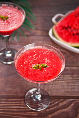 Watermelon refreshing summer frozen cocktail smoothie with watermelon slices and pieces on the background
