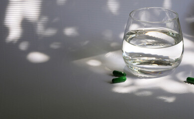 Glass of water with vitamin capsules. Food supplements. Copy space