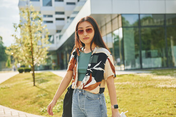Fototapeta na wymiar In sunglasses. Young asian woman is outdoors at daytime