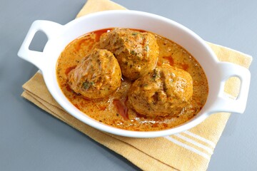 Indian cuisine- Paneer Stuffed dum aloo. Kashmiri Dum Aloo or Potatoes in red gravy over white background. Paneer Bharwa alu. Garnished with coriander. Copy space. Panjabi Dam alu curry.
