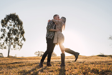 Stylish couple kissing in field in summer