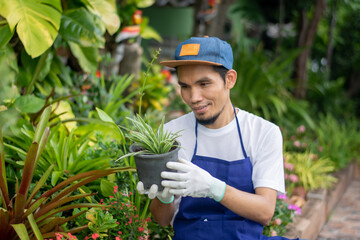 Happy man holding floral pot in garden ornament shop