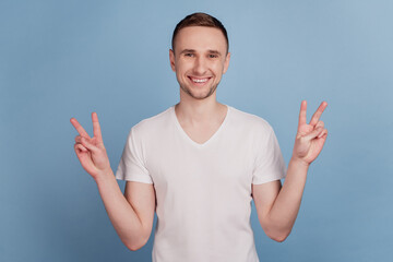 Photo of young handsome man happy smile positive showing v-sign gesture cool isolated on pastel blue color background