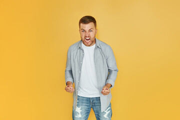 Fells anger. Young man in casual clothes standing indoors in the studio