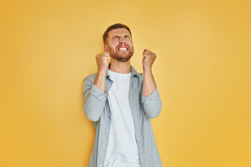 Headache and anger. Young man in casual clothes standing indoors in the studio